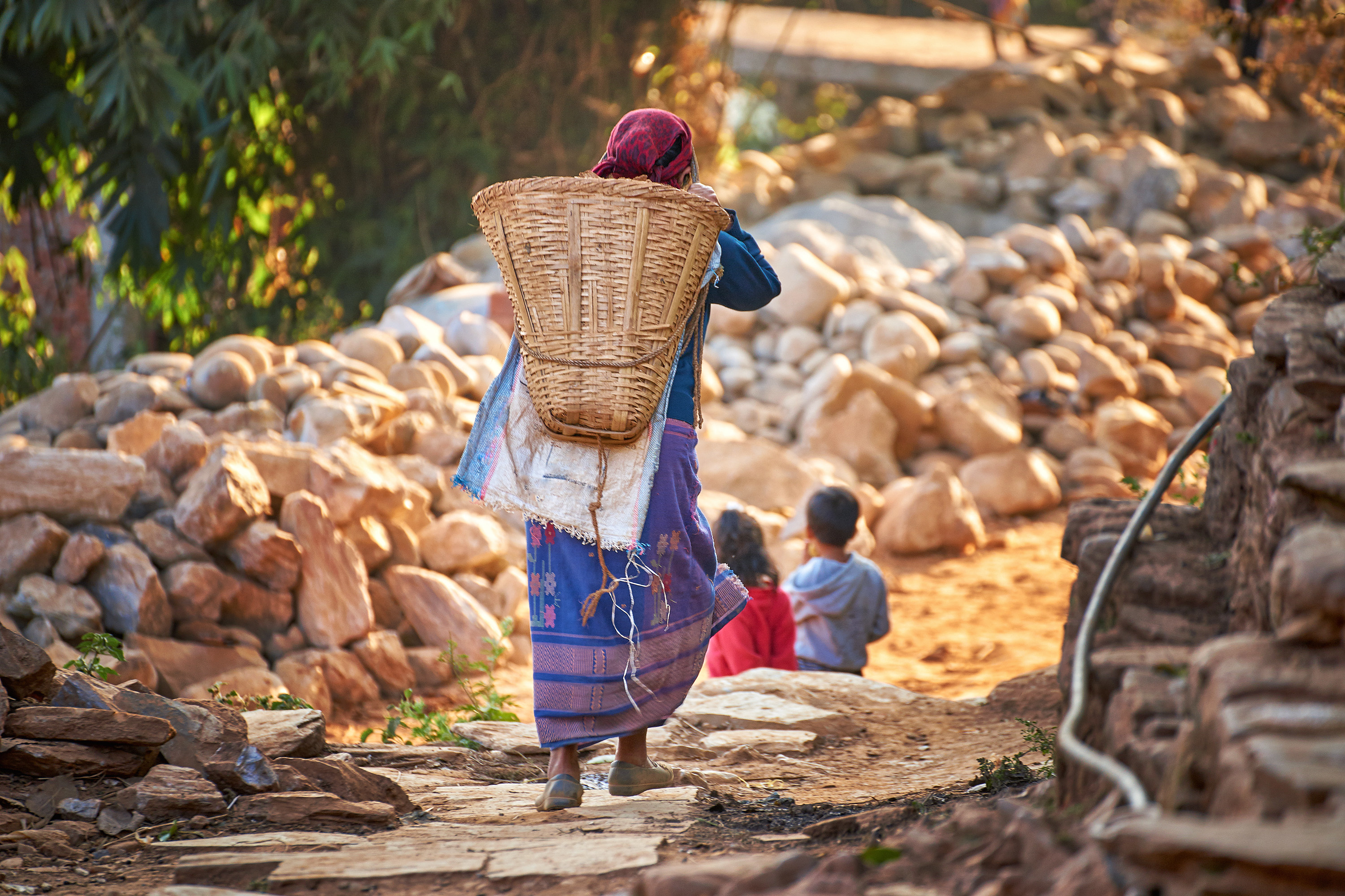 Nepalese woman carries huge wicker basket on her back. Credit: AdobeStock.